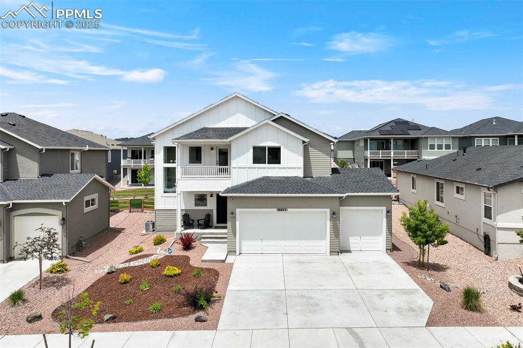 Caption: View of front of house featuring board and batten siding, a balcony, a residential view, and drivewa