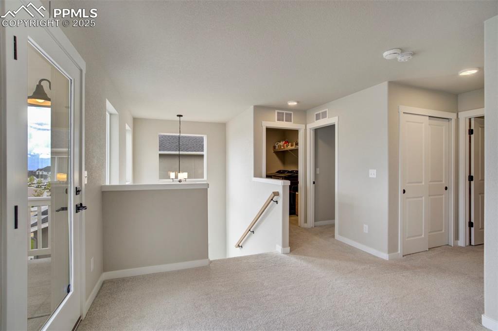 Image 14 of 47: Empty room featuring carpet, baseboards, and a chandelier