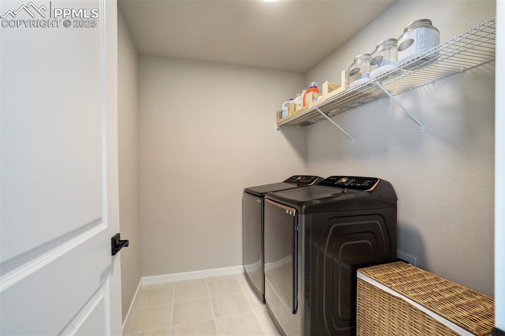Image 27 of 47: Laundry room featuring washer and dryer, baseboards, and light tile pattern