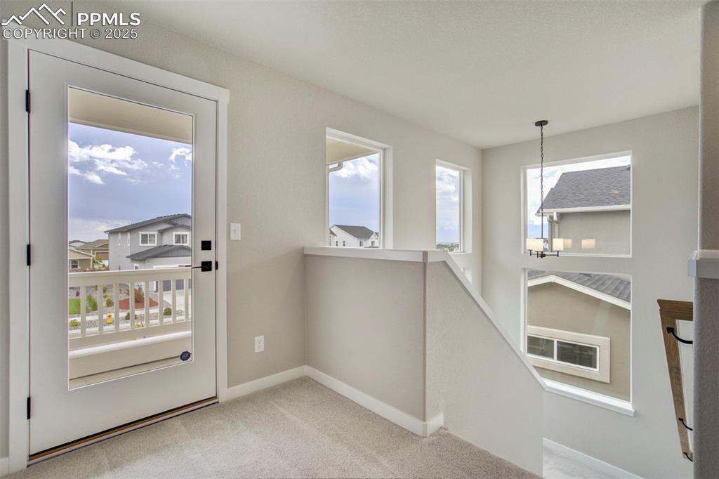 Image 28 of 47: Doorway to outside featuring baseboards and carpet
