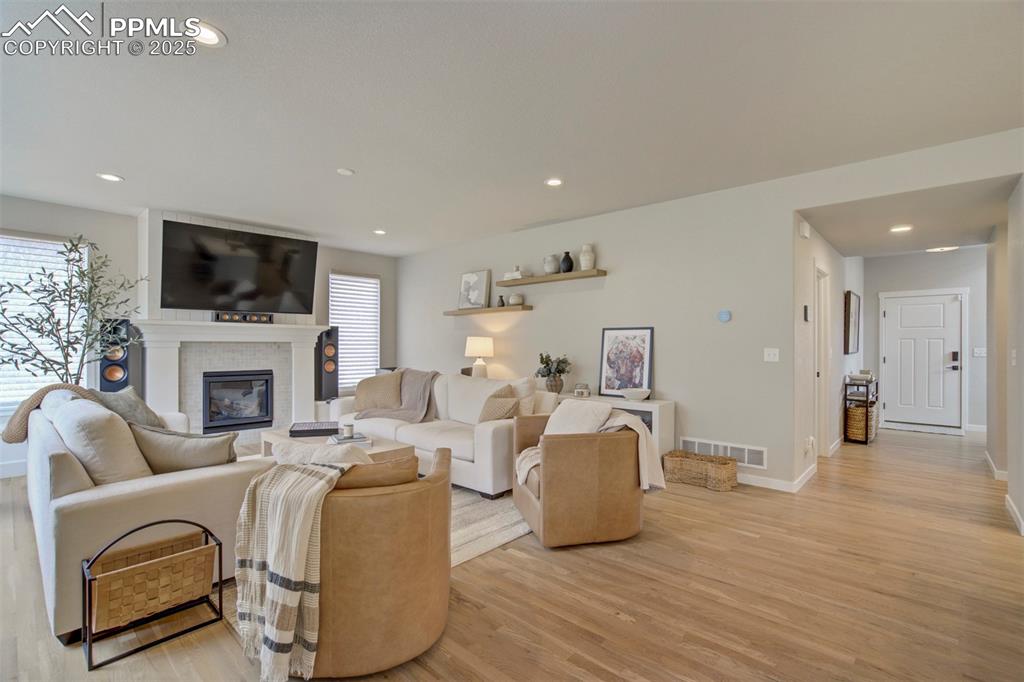 Image 5 of 47: Living room featuring light wood finished floors, a glass covered fireplace