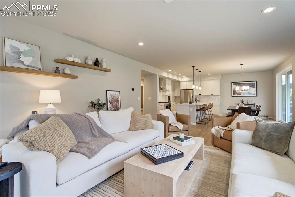 Image 7 of 47: Living room with light wood finished floors, a chandelier, and recessed lig