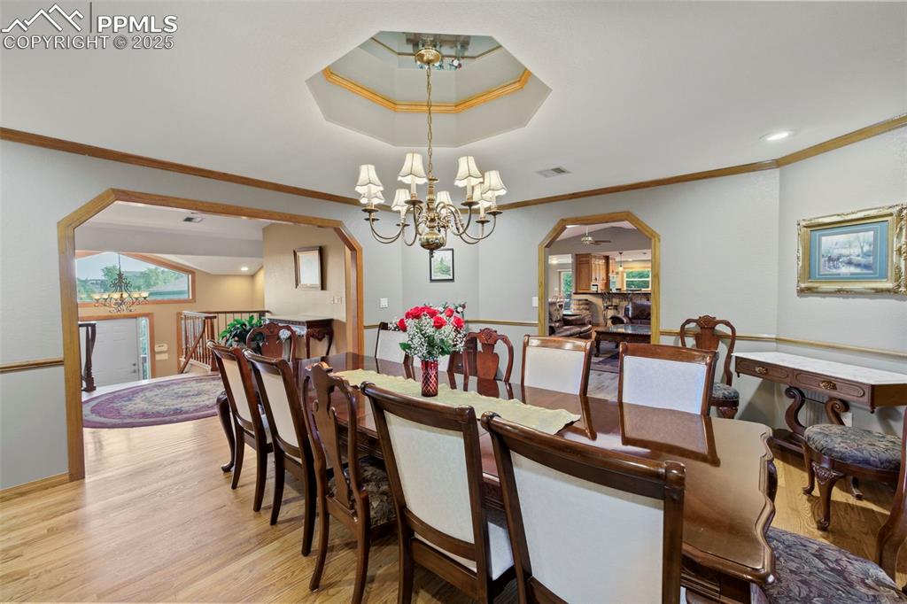 Image 11 of 50: Dining area with a chandelier, arched walkways, light wood-type flooring, c