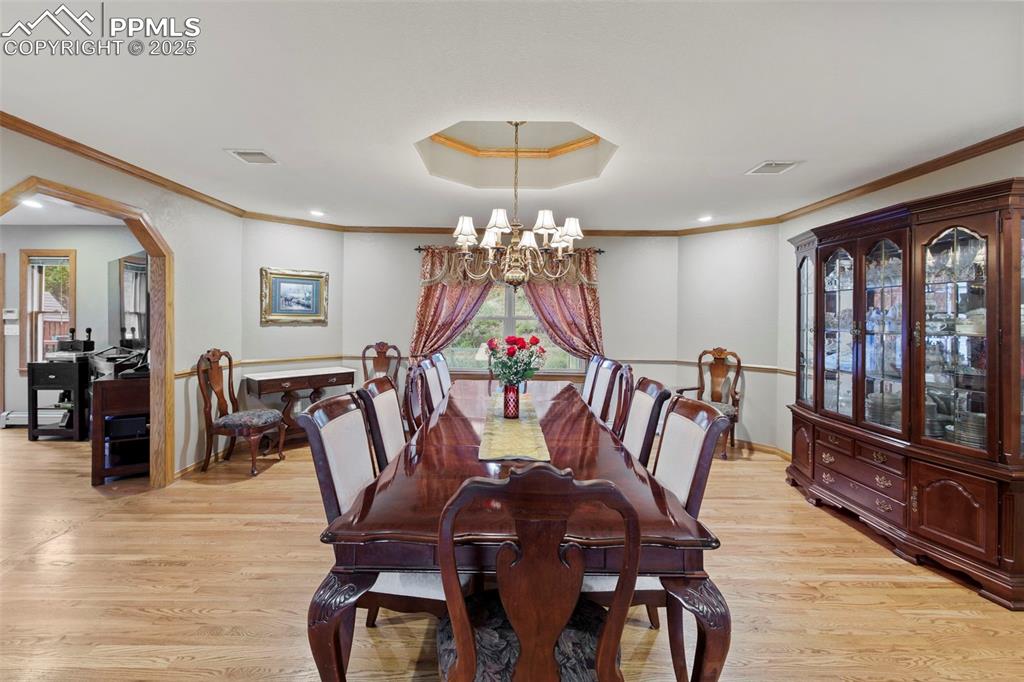 Image 12 of 50: Dining area featuring arched walkways, light wood-style flooring, crown mol