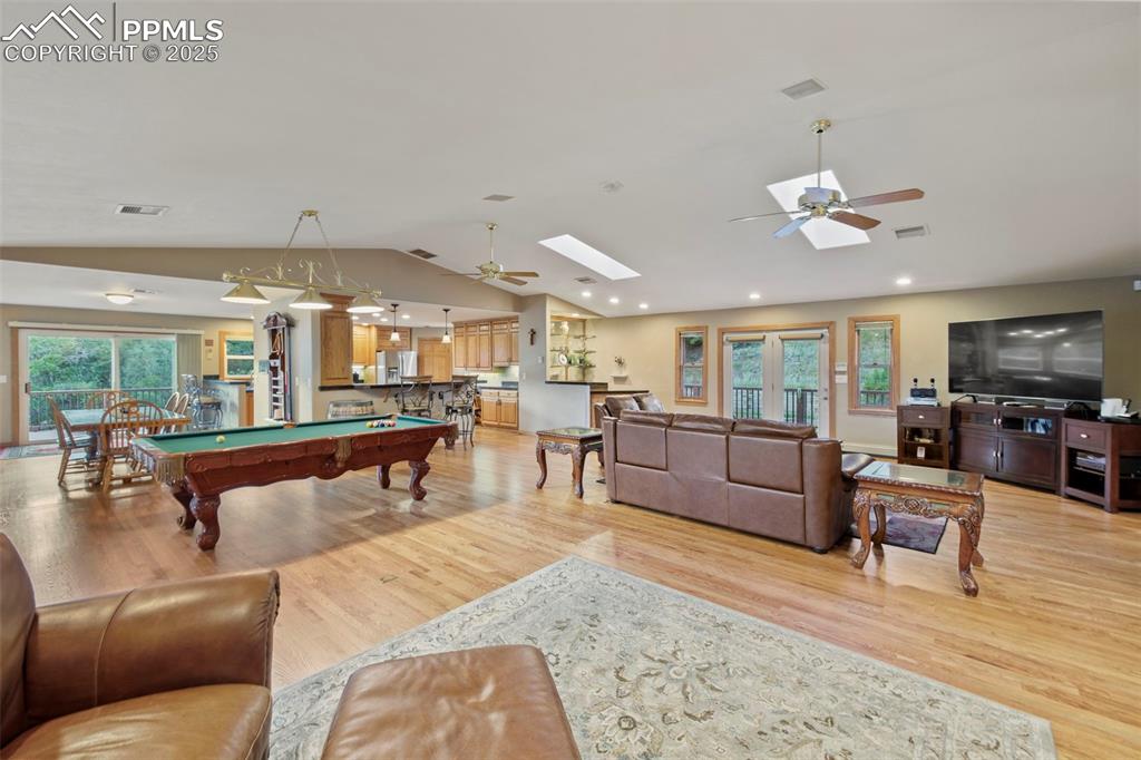 Image 15 of 50: Living area with billiards table, ceiling fan, light wood-style floors, vau