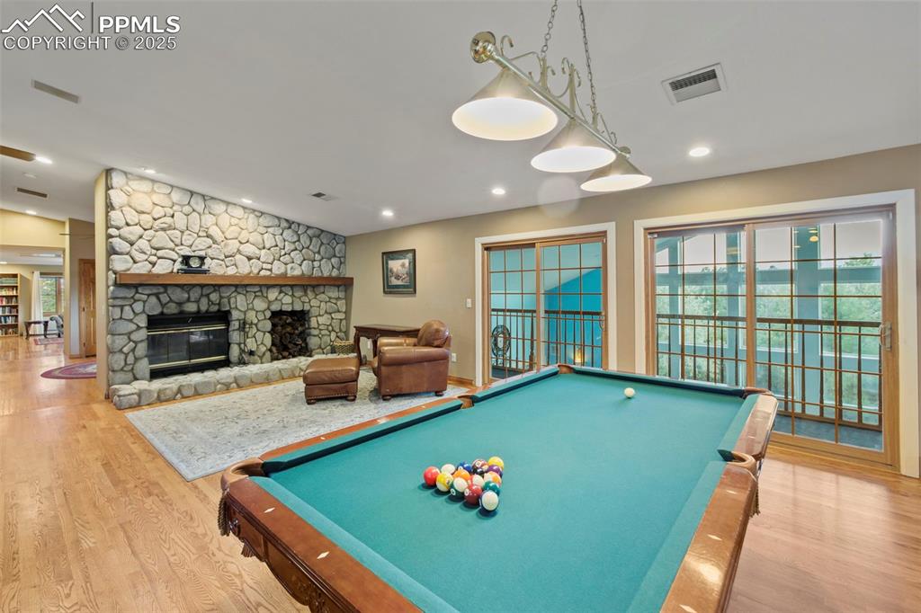 Image 16 of 50: Recreation room featuring light wood-style floors, a fireplace, pool table,