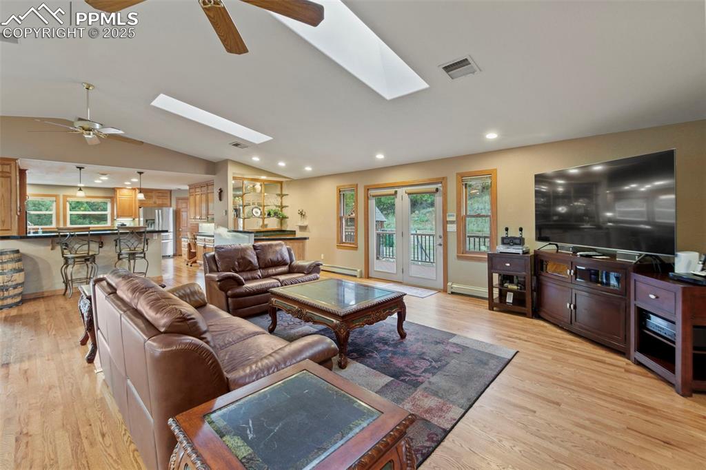 Image 17 of 50: Living room featuring vaulted ceiling, ceiling fan, healthy amount of natur