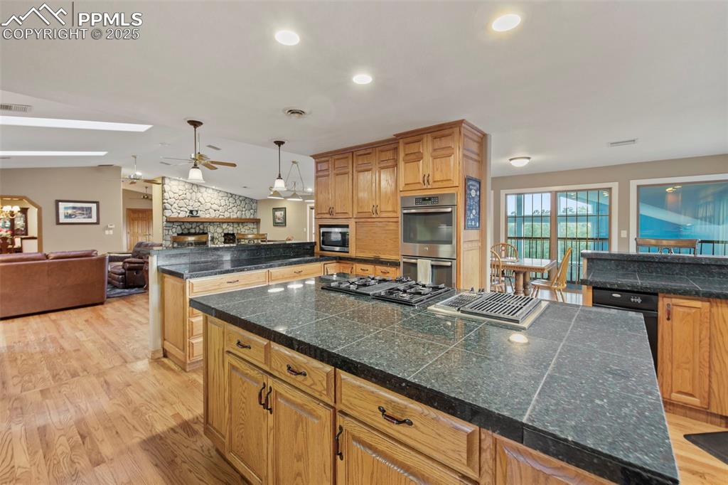 Image 19 of 50: Kitchen with tile counters, a center island, light wood-type flooring, loft