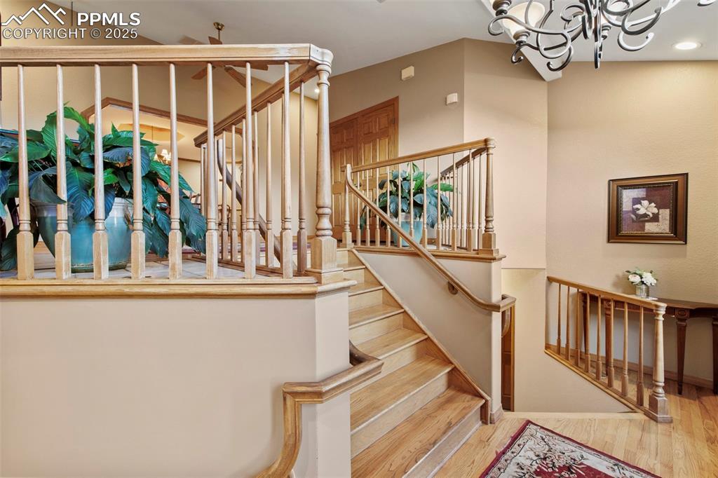 Image 2 of 50: Stairway with wood finished floors, a chandelier, and recessed lighting