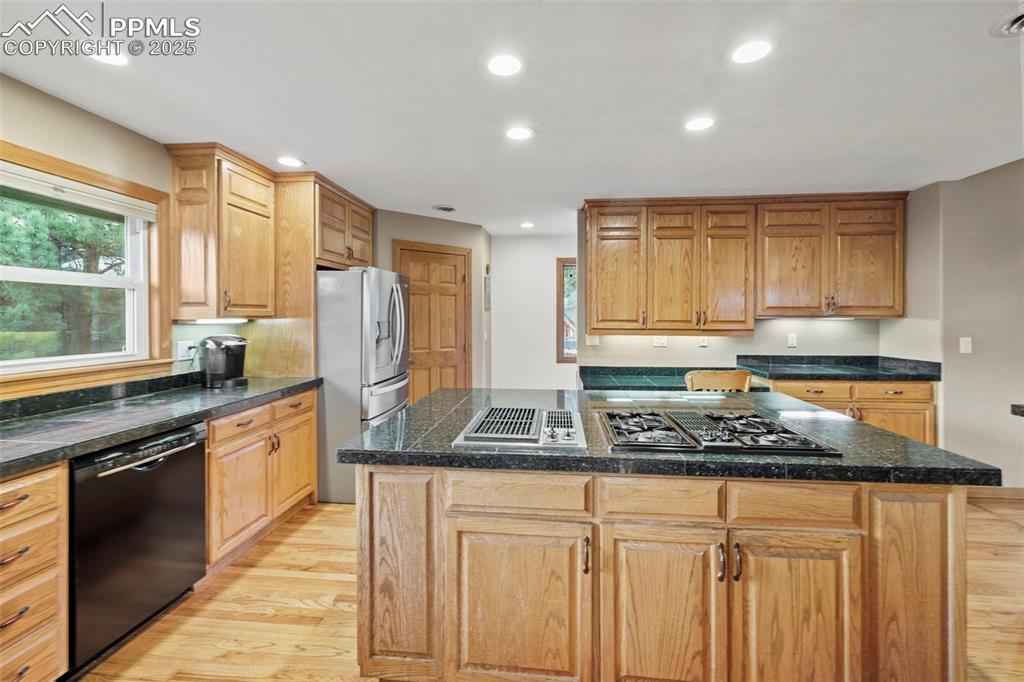 Image 21 of 50: Kitchen with tile counters, light wood finished floors, stainless steel app