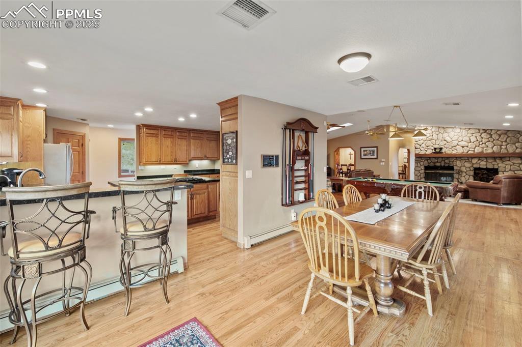 Image 22 of 50: Dining space featuring baseboard heating, recessed lighting, a fireplace, l