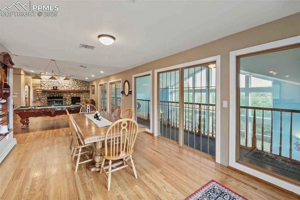 Image 23 of 50: Dining area featuring a fireplace, light wood-type flooring, pool table, re