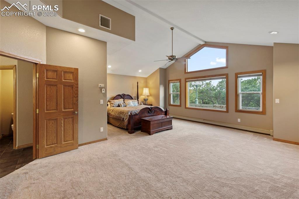 Image 26 of 50: Bedroom featuring light carpet, a baseboard heating unit, high vaulted ceil