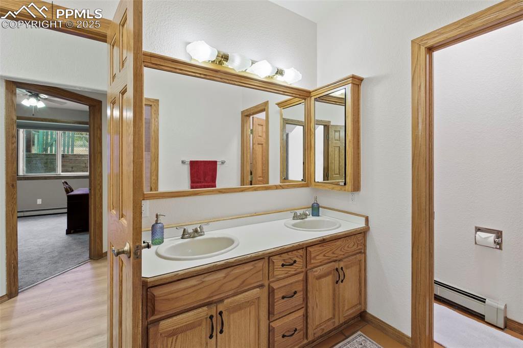 Image 31 of 50: Bathroom featuring double vanity, a baseboard heating unit, light wood-type