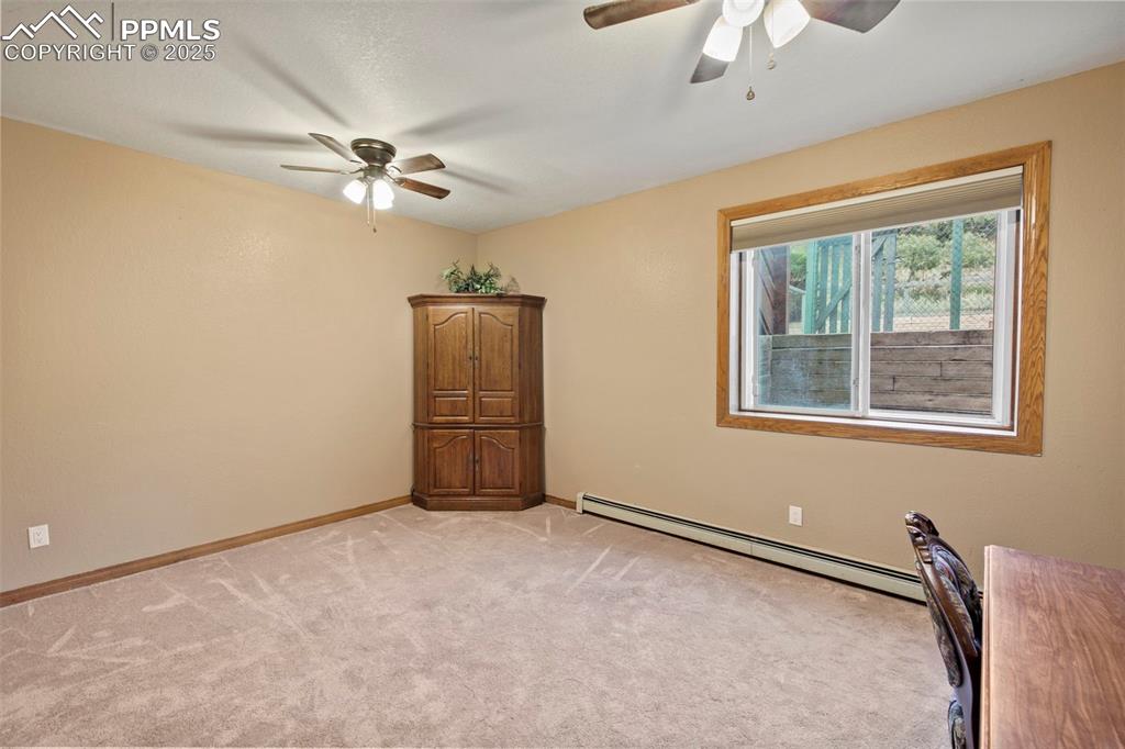 Image 32 of 50: Unfurnished bedroom featuring ceiling fan, a baseboard heating unit, and li
