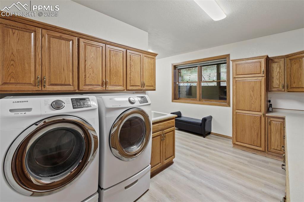 Image 34 of 50: Laundry room with light wood-style flooring, cabinet space, and separate wa
