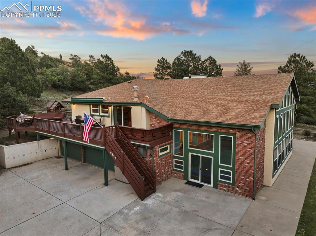 Image 48 of 50: Back of house with brick siding, a shingled roof, concrete driveway, and a 