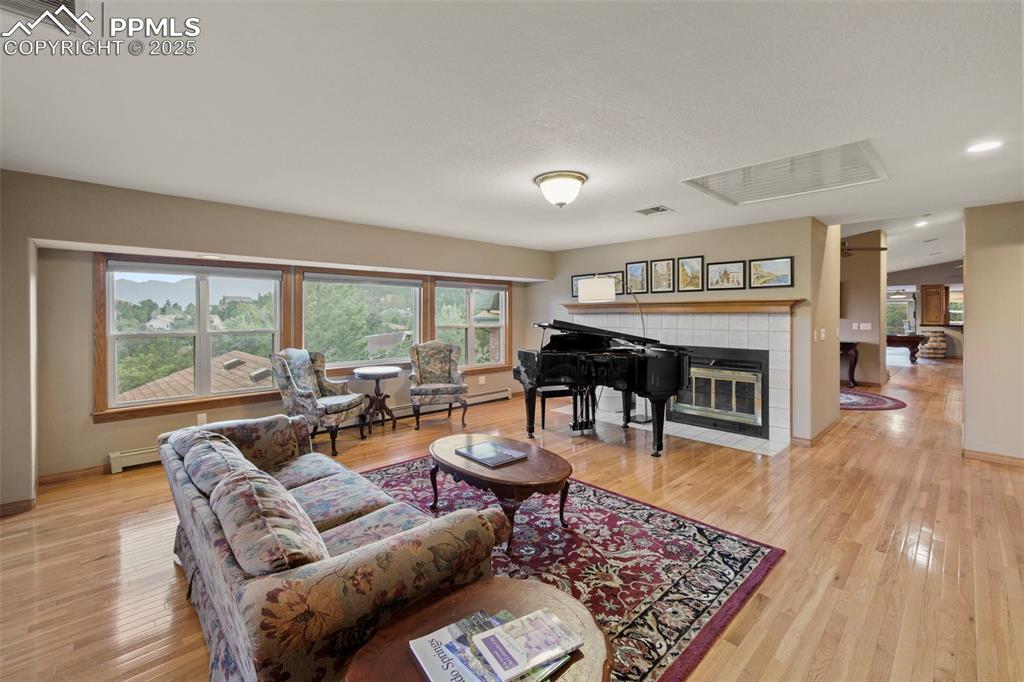 Image 5 of 50: Living room featuring light wood-type flooring, a tile fireplace, baseboard