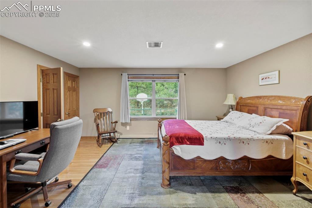 Image 7 of 50: Bedroom featuring wood finished floors, recessed lighting, and a desk