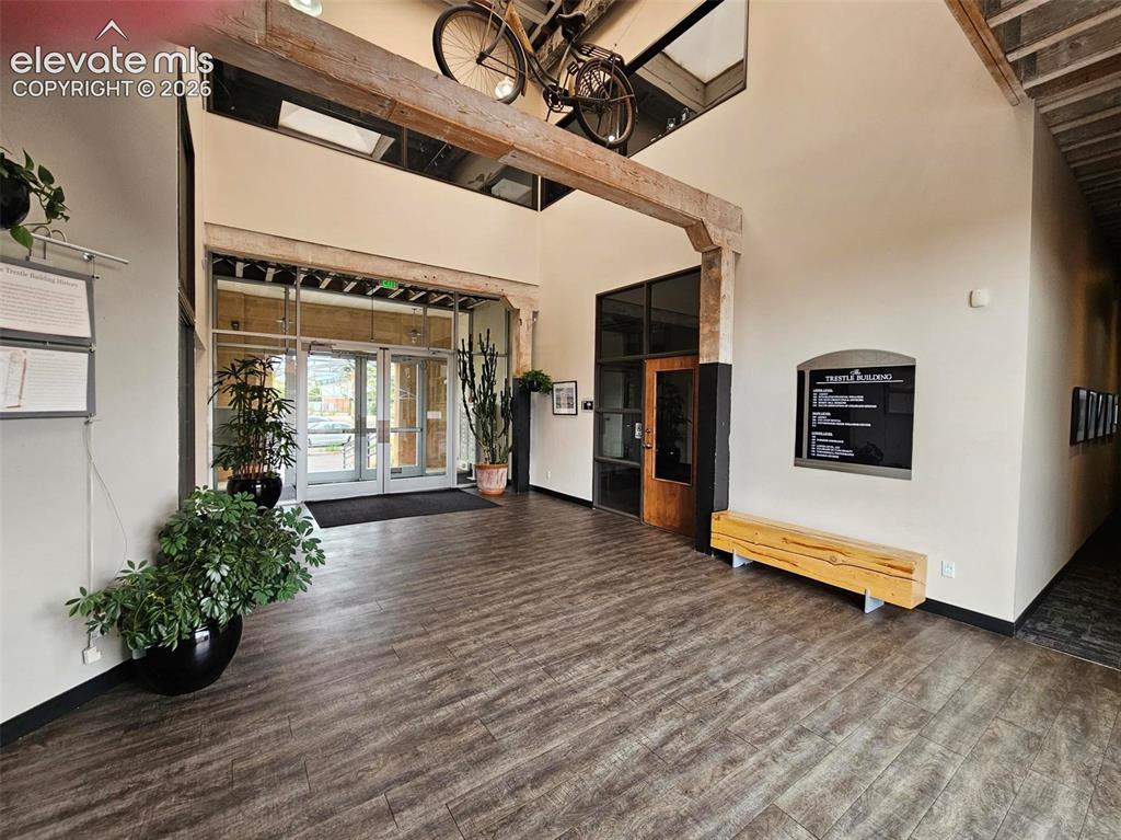 Image 2 of 11: Spacious entry with wood-finish flooring, exposed wood beams, high ceilings