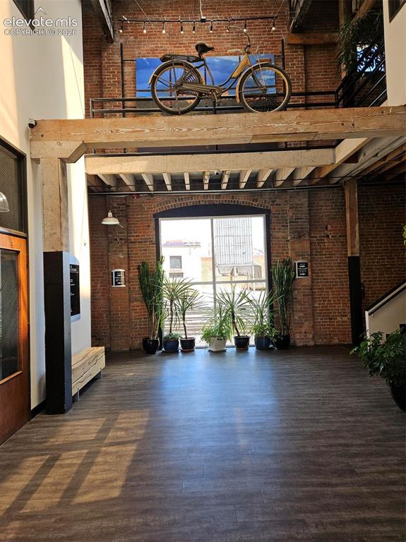 Image 3 of 11: Spacious interior featuring exposed brick walls, wood-finish flooring, and 