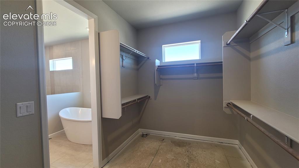 Image 14 of 29: One of two primary walk-in closets with wood shelving, rods, and windows! P