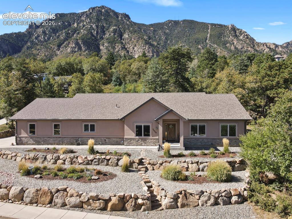 Image 1 of 46: Single-story residence with stone veneer facade, shingle roof, multi-level