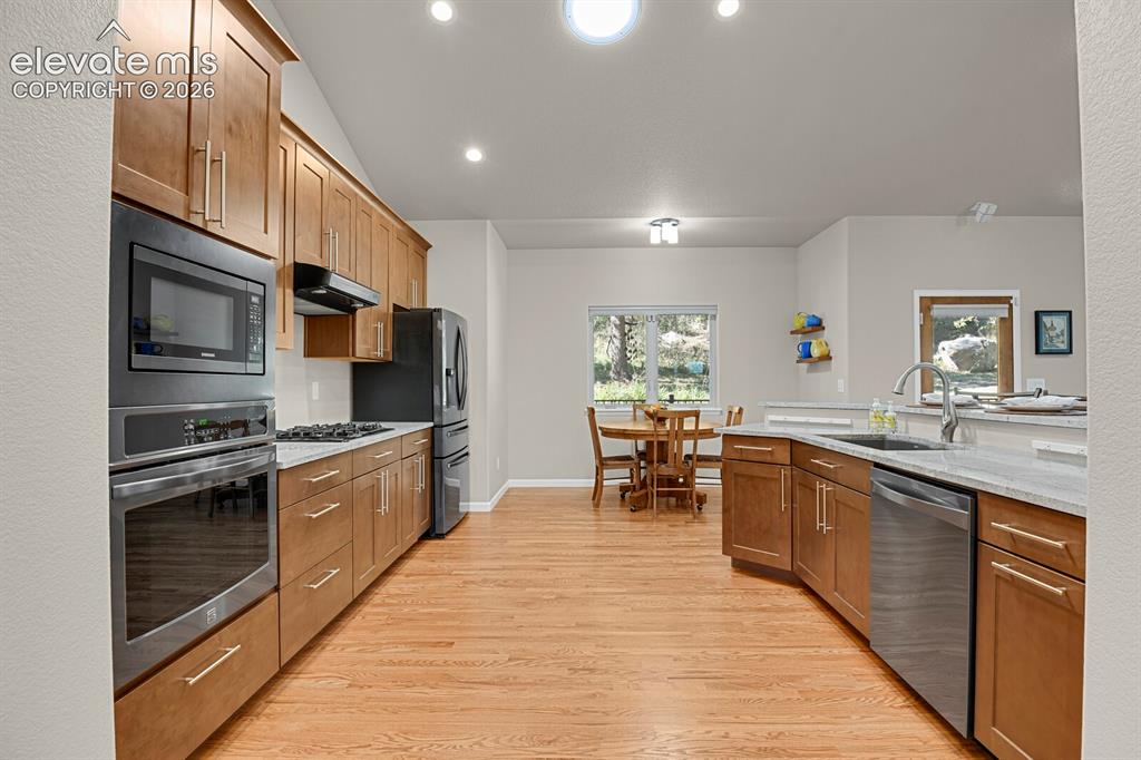 Image 15 of 46: Kitchen featuring wood-finish cabinetry, stone-surface countertops, stainle