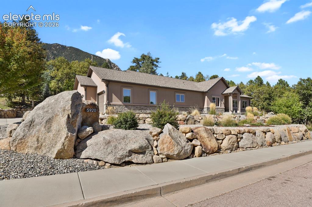 Image 2 of 46: Single-story residence featuring a stucco and stone veneer exterior, a conc