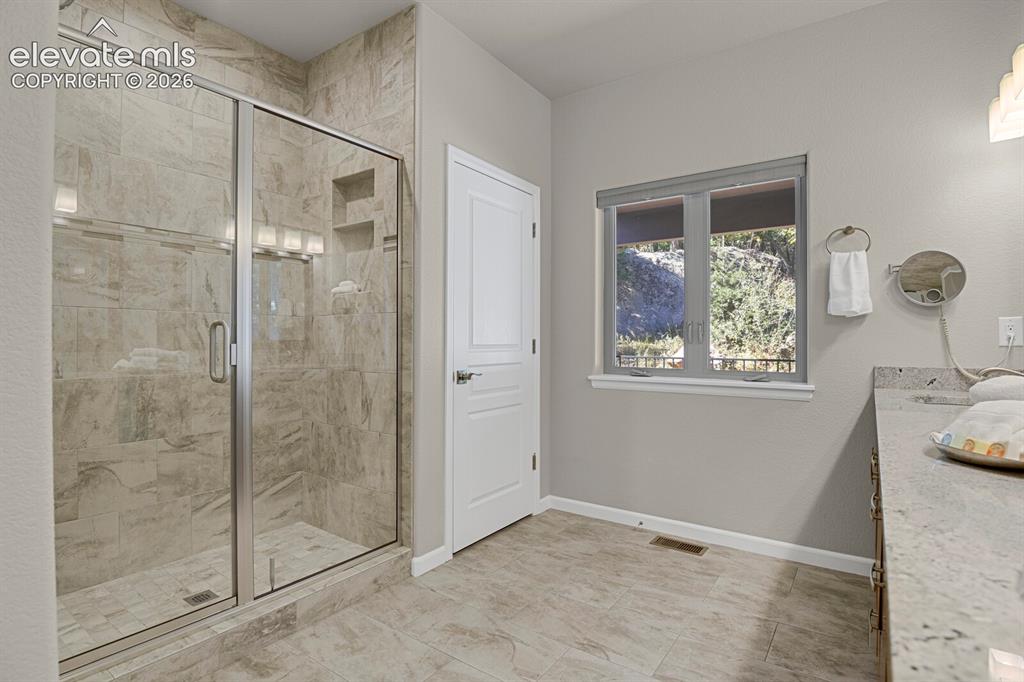 Image 24 of 46: Walk-in shower with floor-to-ceiling stone-pattern tile, built-in shelving,