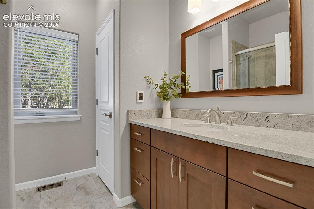 Image 27 of 46: Bathroom vanity featuring a stone countertop, under-mount sink, brushed nic