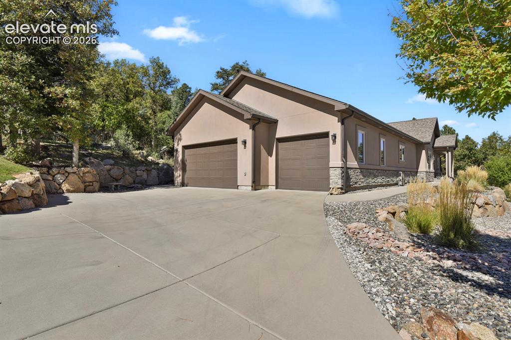 Image 3 of 46: Stucco exterior with stone veneer accents, attached three-car garage, concr