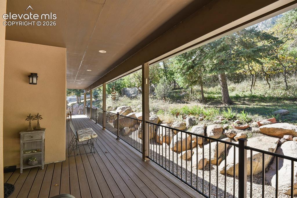 Image 33 of 46: Covered deck featuring wood-finish decking, black metal balustrades, recess