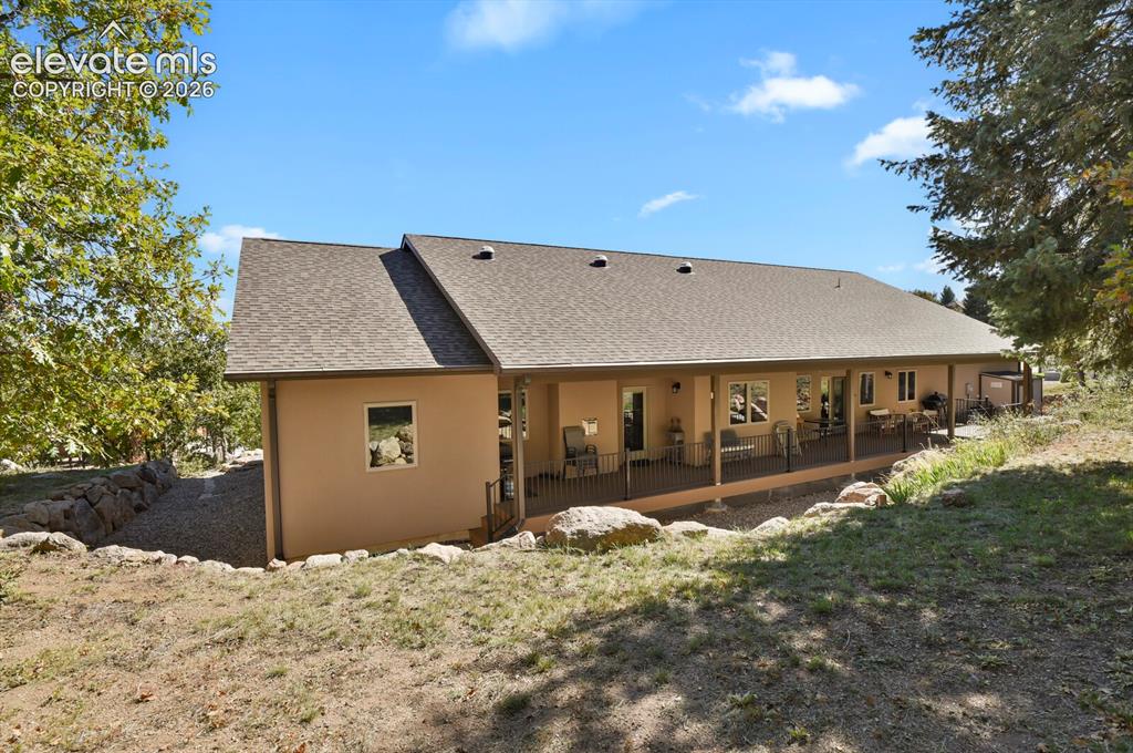 Image 35 of 46: Exterior featuring a covered wrap-around porch with metal railing, stone re