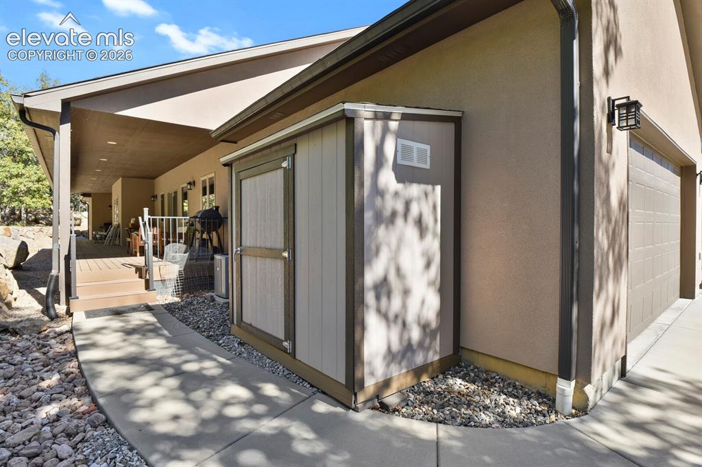 Image 36 of 46: Exterior space featuring a concrete walkway, attached storage structure, co