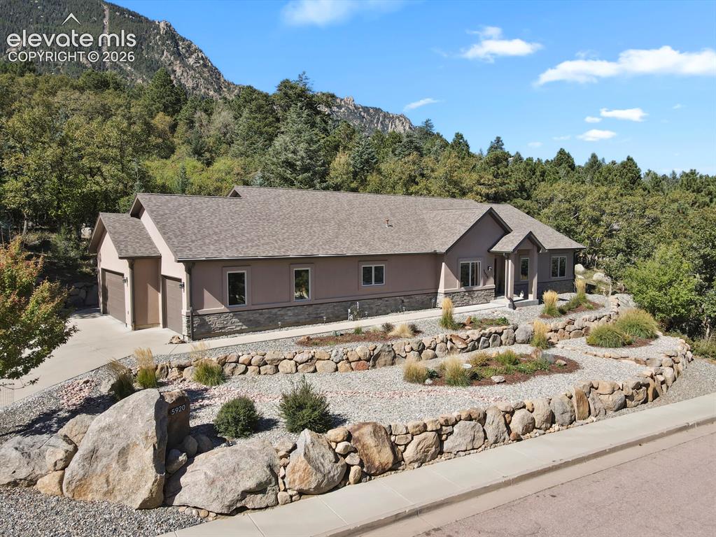 Image 38 of 46: Multi-level stone retaining walls, stucco and stone exterior, attached thre
