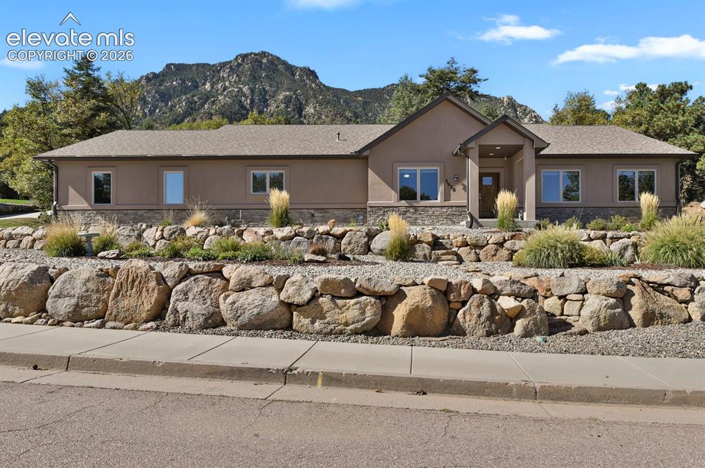 Image 4 of 46: Single-story residence featuring a stucco and stone exterior, multi-tiered