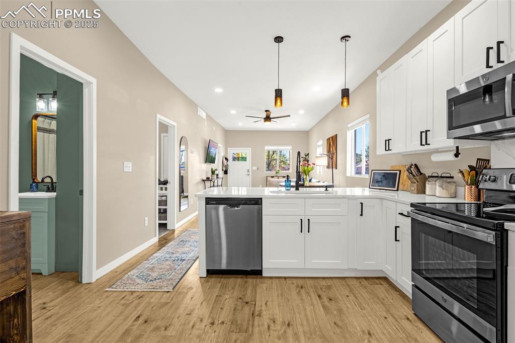 Image 10 of 36: Kitchen with appliances with stainless steel finishes, a peninsula, white c