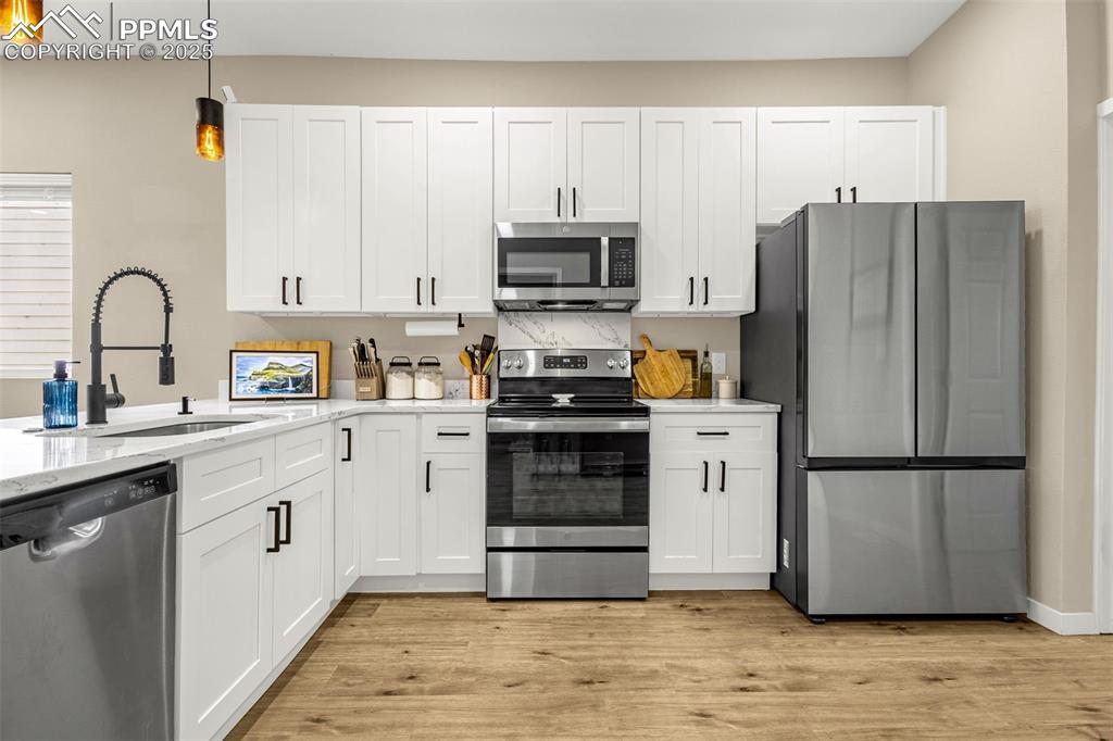 Image 11 of 36: Kitchen with appliances with stainless steel finishes, a sink, white cabine