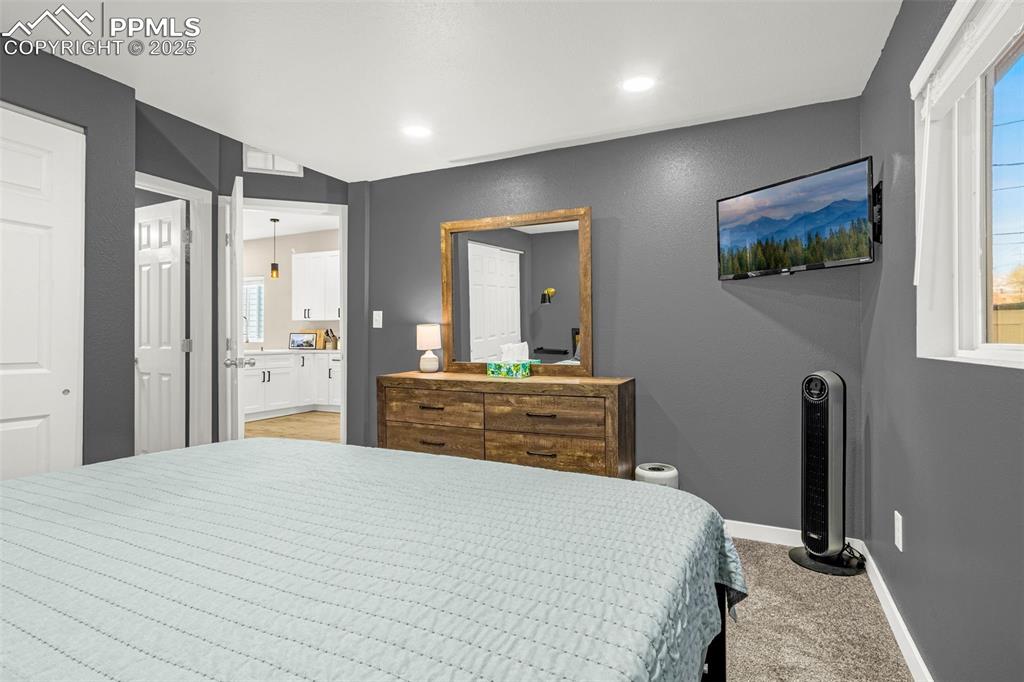 Image 12 of 36: Bedroom with baseboards, light carpet, ensuite bath, and lofted ceiling