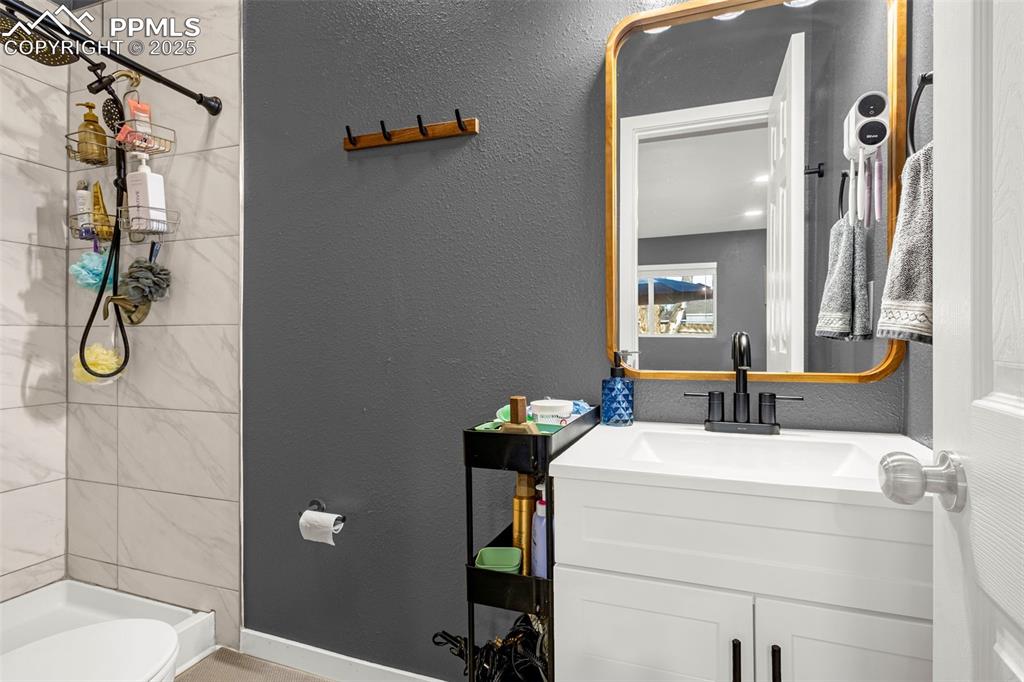 Image 15 of 36: Full bathroom featuring a tile shower, vanity, toilet, and baseboards