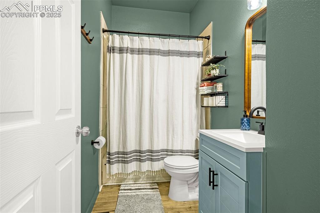 Image 19 of 36: Bathroom with wood finished floors, vanity, toilet, and shower / bath combo