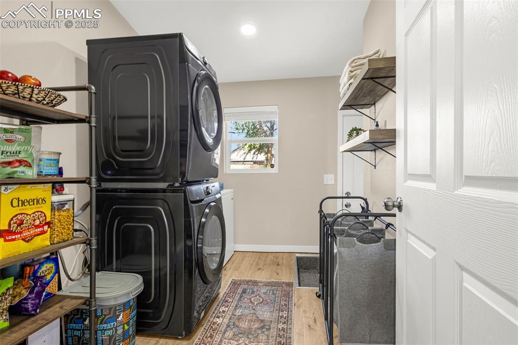 Image 21 of 36: Laundry area with stacked washer and clothes dryer, light wood-type floorin