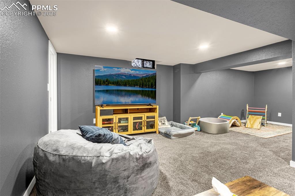 Image 24 of 36: Carpeted living area with a textured wall, baseboards, stairs, and recessed