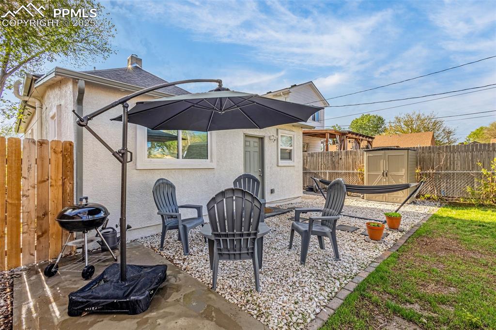 Image 28 of 36: Back of property with stucco siding, a fenced backyard, an outdoor structur