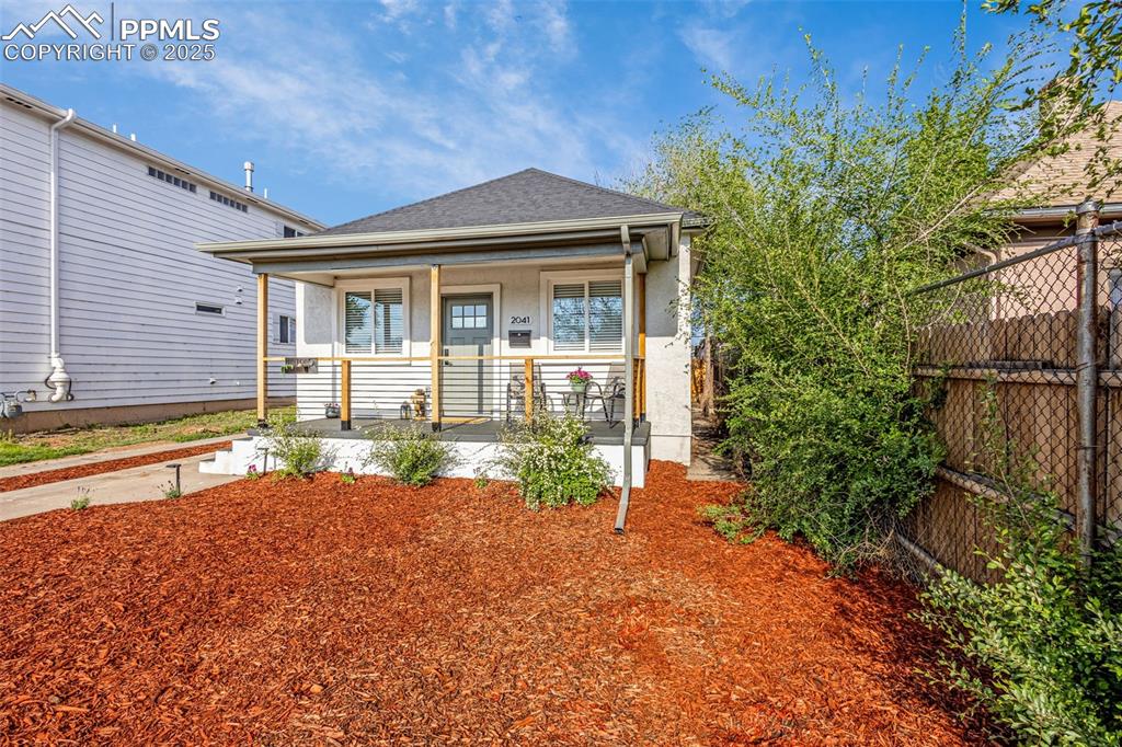Image 4 of 36: View of front of house with a porch, fence, stucco siding, and driveway