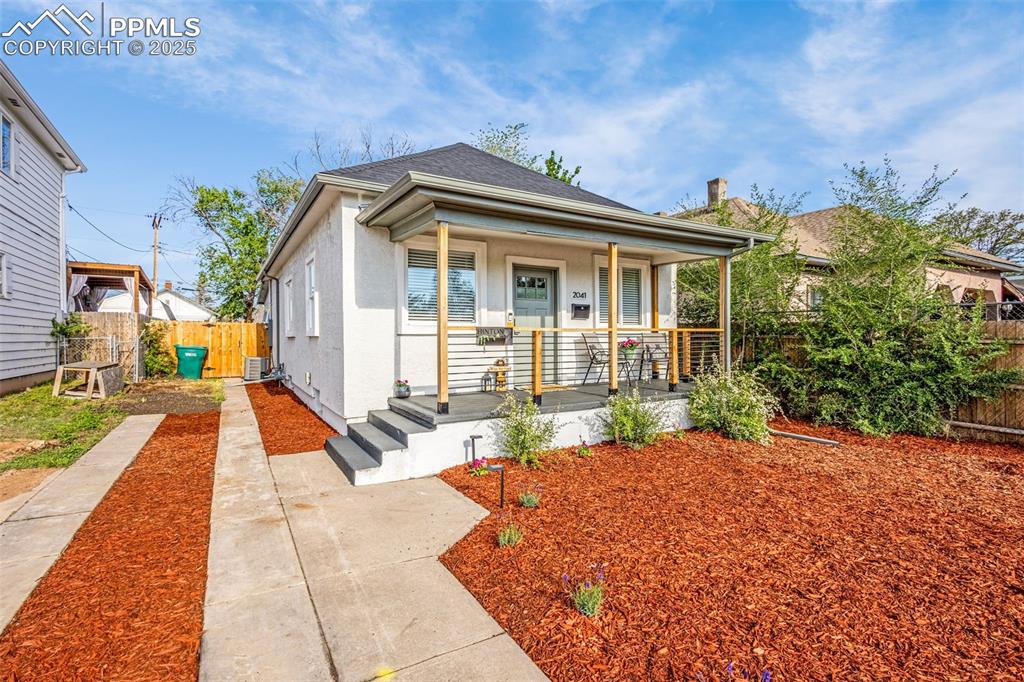 Image 5 of 36: View of front of house with a porch, fence, stucco siding, and central AC u