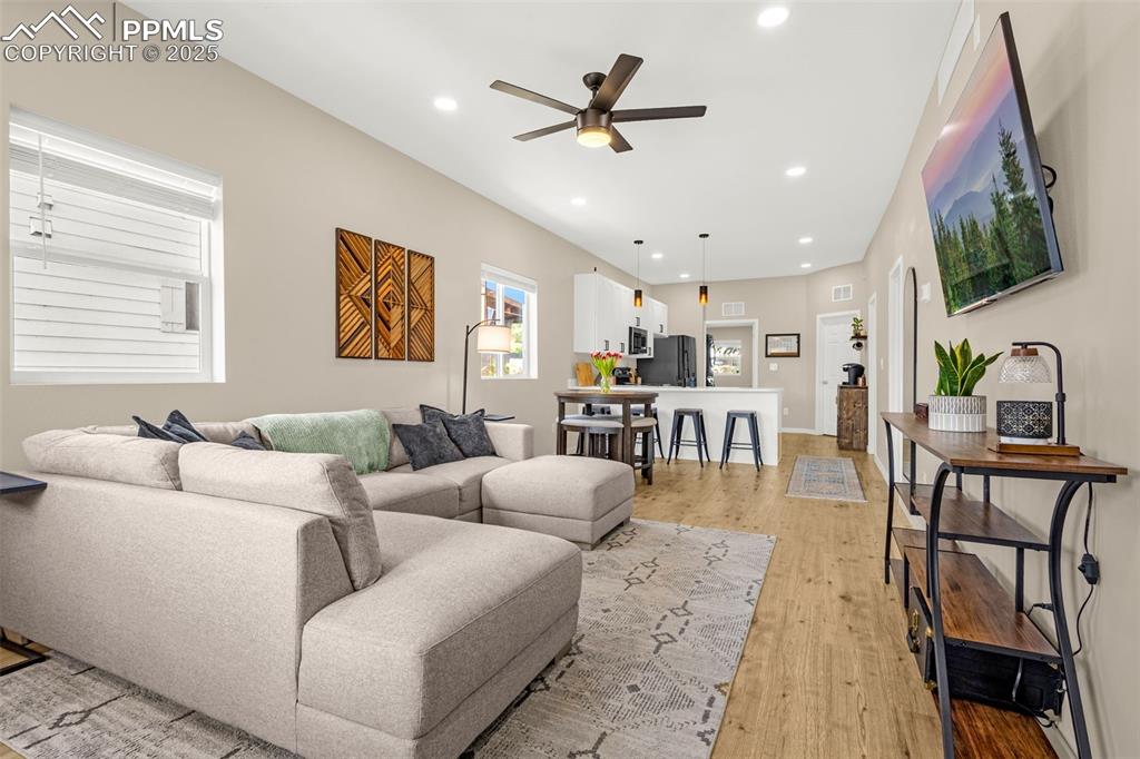 Image 6 of 36: Living area featuring ceiling fan, light wood finished floors, and recessed