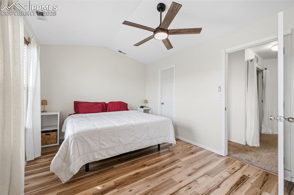 Image 16 of 30: Bedroom with lofted ceiling, light wood-style floors, and ceiling fan