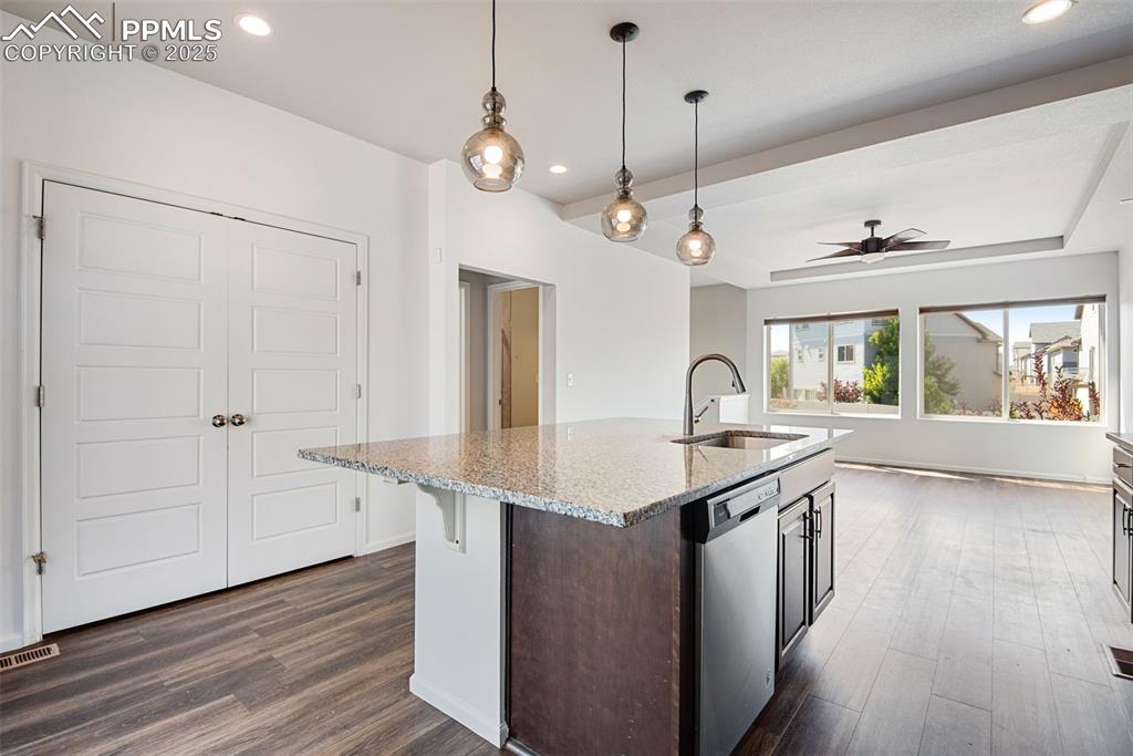 Image 13 of 39: Kitchen featuring pendant lighting, light stone counters, dark wood-style f
